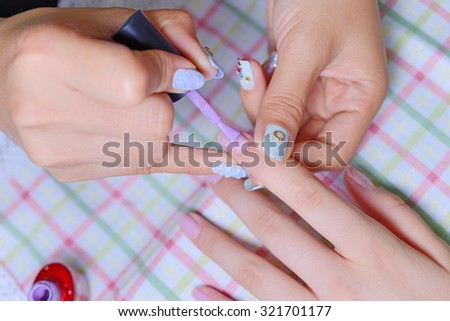 Closeup of woman applying nail varnish to finger nails at nail salon