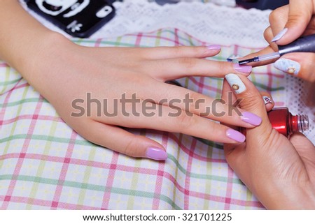 Closeup of woman applying nail varnish to finger nails at nail salon
