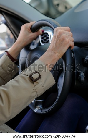 Senior woman hand on steering wheel of her car.