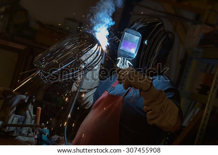 Welder wearing face mask and protective gloves in factory