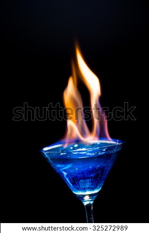 Fire blowing out of blue lagoon glass/close-up with black background and laser effects