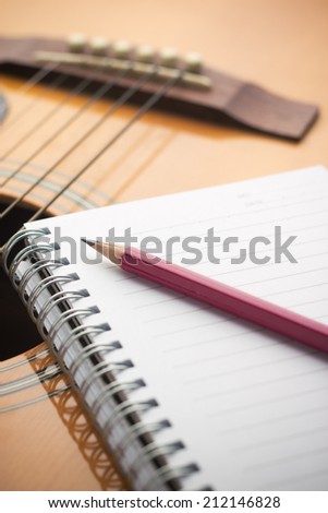 Notebook and pencil on guitar, Writing music