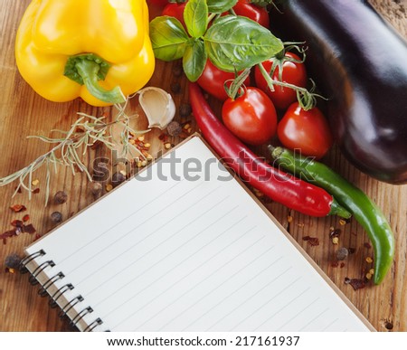Food background with paper for notes., tomatoes,  condiments, eggplants, pepper and basil on a wooden table.