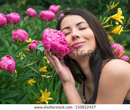 Young woman smelling a flower peony