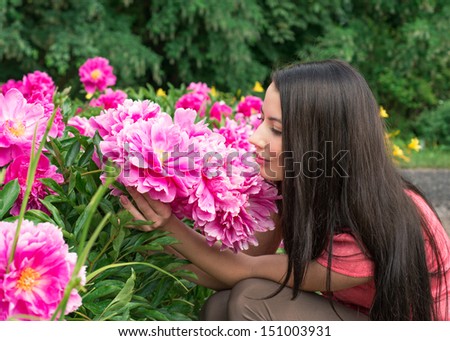 Young woman smelling a flower peony