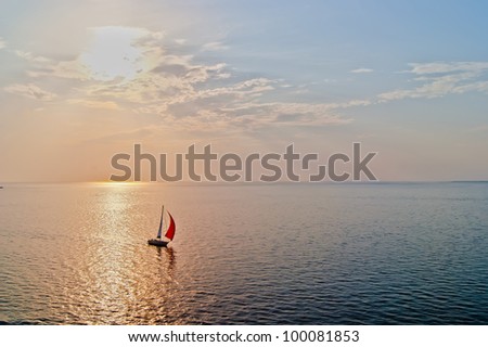 A solitary sailboat in the open sea at the sunset, bird\'s-eye view