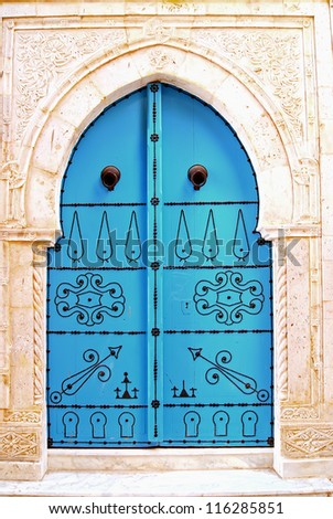 A blue door with black studs and stone ornament at doorway in Tunisia