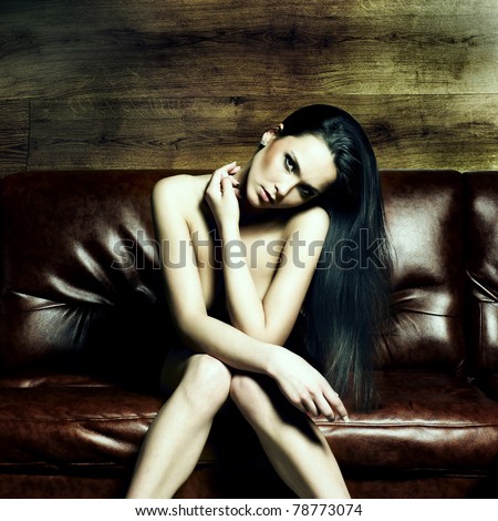 Portrait of a beautiful naked young woman on a leather sofa