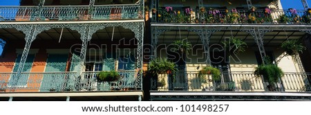This shows two buildings in the historic French Quarter on Bourbon Street. The buildings have lattice work railings with potted flowers decorating the balconies.