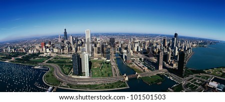 This is an aerial view of the Chicago skyline, Lake Michigan and the Chicago Harbor on left during summer.  Boats are moored in the harbor and Lake Shore Drive winds around the city.