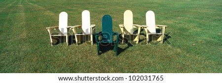 This is an image of five wooden lawn chairs against a green lawn background.