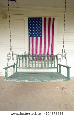 Old swing on porch displaying an American Flag and patriotic theme