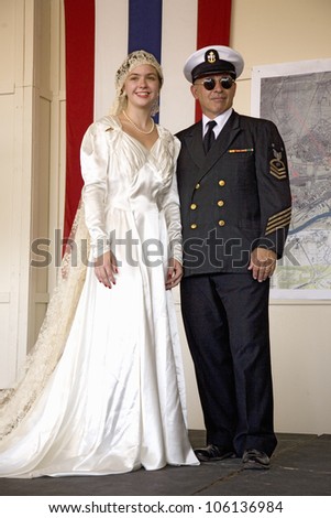 Bride in 1940s wedding dress posing with her father in a Navy Officer, reenactment of a World War II fashion show at the Mid-Atlantic Air Museum World War II Weekend in Reading, PA held June 18, 2008