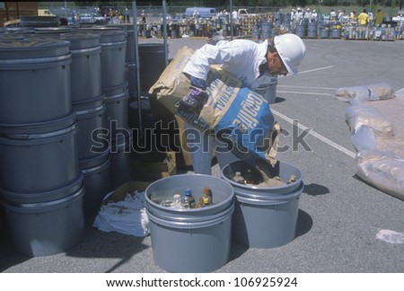 CIRCA 1990 - A worker pouring the contents of a bag into a container of waste materials at waste cleanup site on Earth Day at the Unocal plant in Wilmington, Los Angeles, CA