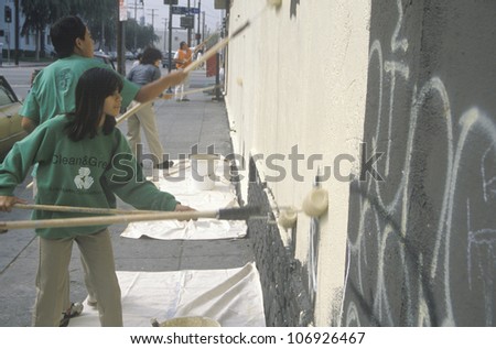 CIRCA 1990 - Several community members participate in covering graffiti for Clean & Green Day, an urban cleanup pro+B302ject in East Los Angeles, CA