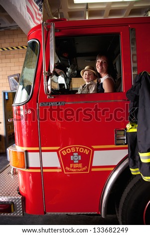 BOSTON - MAY 11: Mother and son pose in fire truck at Ladder #1, Engine #8, Firestation on May 11, 2012 in historic North End, Italian section of Boston, MA
