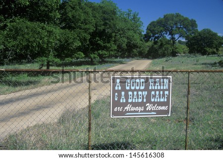 Sign on Willow Loop City Road, north of Fredericksburg, TX reading \'A Good Rain, A Baby Calf, are Always Welcome\'