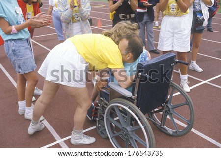 Special Olympics athlete in wheelchair, crossing finish line, being congratulated, UCLA, CA