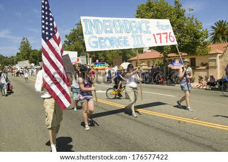 Parade participants carrying banner protesting George W. Bush make their way down main street during a Fourth of July parade in Ojai, CA