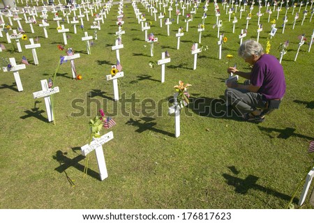 Woman kneels at mock cemetery honoring 1500+ Iraqi servicemen killed in Iraq War, Ventura California