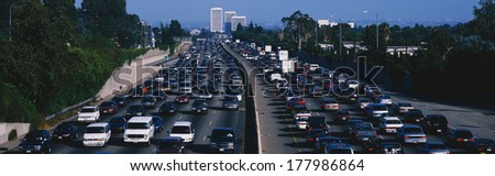 This is rush hour traffic on the 405 Freeway at sunset. There are 10 lanes of traffic total showing both sides of the freeway. There are cars stopped in every lane.