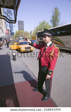 Bellman in red jacket calls for cab in front of Helmsley Park Lane Hotel on Central Park West, in Manhattan, New York City, New York