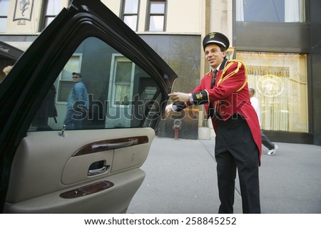 Bellman in red jacket opens limo door in front of Helmsley Park Lane Hotel on Central Park West, in Manhattan, New York City, NY