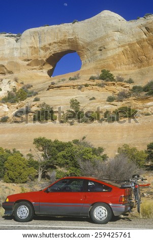 Window Rock Arch in southern UT with red car in foreground