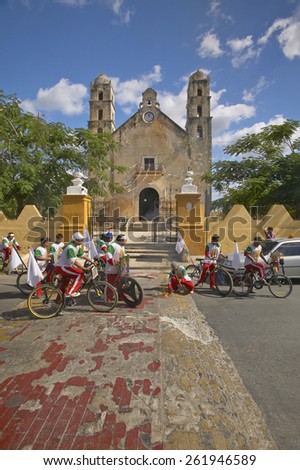 Young men bicycle in front of Catholic cathedral of Izamal and light torch in the Yucatan Peninsula, Mexico