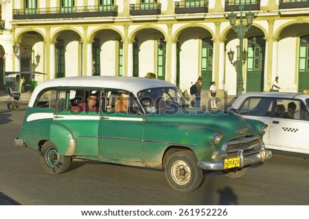 An old American green car and taxi driving through Old Havana, Cuba