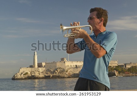 A trumpet player playing music in front of Castillo del Morro, El Morro Fort, across the Havana channel, Cuba