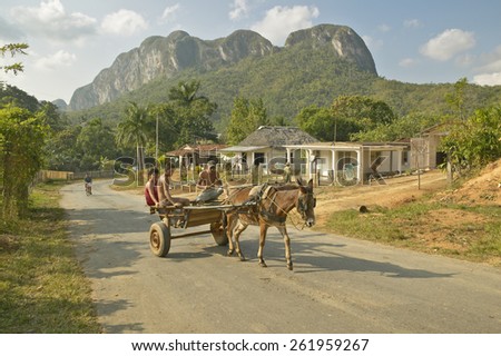 Horse drawn cart traveling in front of house in the Valle de Vinales, in central Cuba