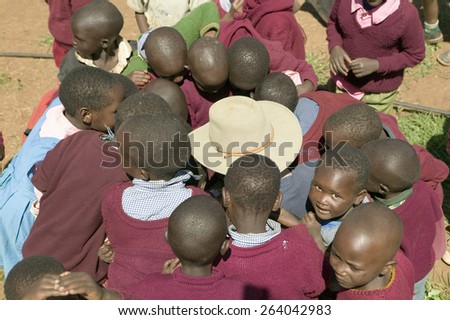 Karimba School with school children surrounding white man with straw hat on, in North Kenya, Africa