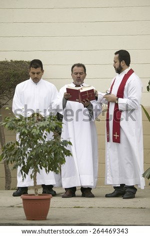 Three priests reading from the bible on Good Friday, Easter,Our Lady of Guadalupe Parish, Oxnard, California, April 6, 2007.