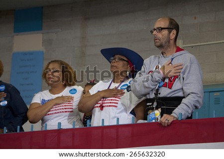 White man and black woman put hand on heart for pledge of allegiance at President Obama campaign rally at Orr Middle School in Las Vegas, October 26, 2012