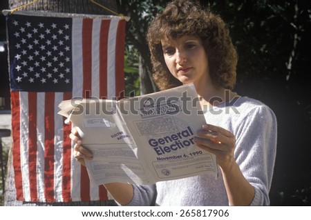 Woman voter reading election pamphlet at the entrance to a polling place, CA