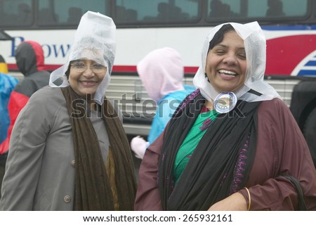 Two women in plastic rain hats pose in in front of bus at the official opening ceremony of the Clinton Presidential Library November 18, 2004 in Little Rock, AK