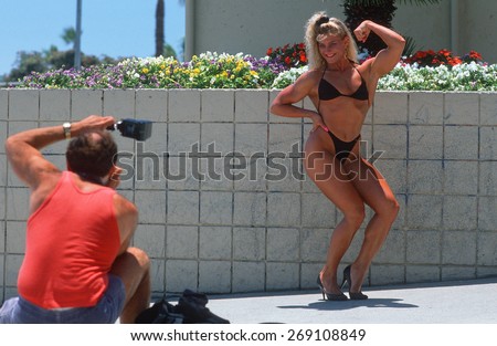 A female body builder flexing for the camera, Venice Beach, CA