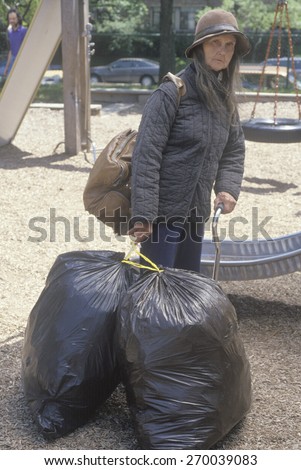 Elderly homeless woman holding possessions in garbage bags, Chicago, Illinois