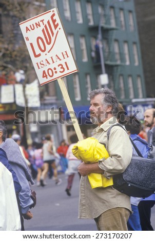Man on street corner with sign during NY City Marathon, NY
