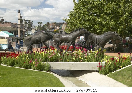 A sculpture of running horses and beautiful spring flowers in Old Town of Scottsdale, Arizona