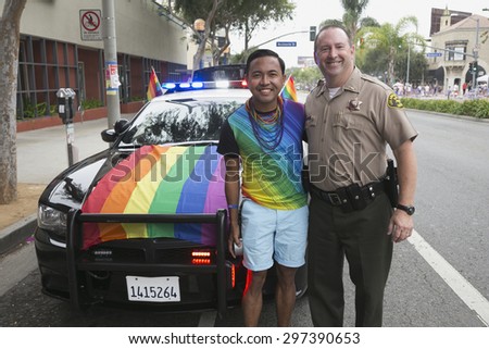 West Hollywood, Los Angeles, California, USA, June 14, 2015, 40th annual Gay Pride Parade for LGBT Community, down Santa Monica Blvd., LA Police Dept. with Rainbow LGBT flag on car poses with gay male