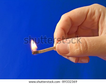 A hand holding a fired matchstick