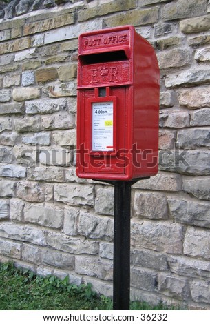 UK postbox as found in English rural villages. This example on a black pole, and with a limestone wall as backdrop