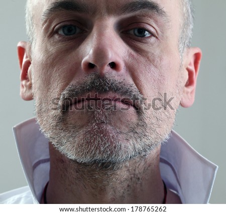 adult thin unshaven gray-haired man in a white shirt emotional