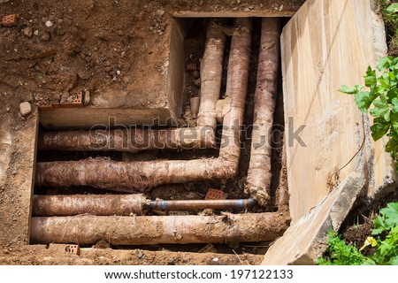 Concrete water trough metal pipes. Pit deep in the ground