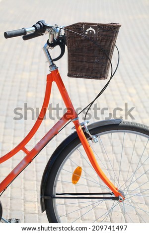 orange bicycle with a basket on the handlebars