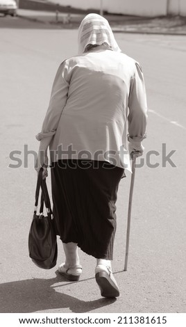 old woman with a cane back view.outdoors