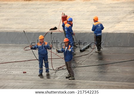 workers in hard hats are placed on concrete roofing material. Belarus,Minsk,September,14,2014