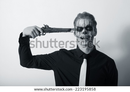 Portrait of serious man with Halloween skull makeup. Halloween or horror theme.gun to his head for suicide
